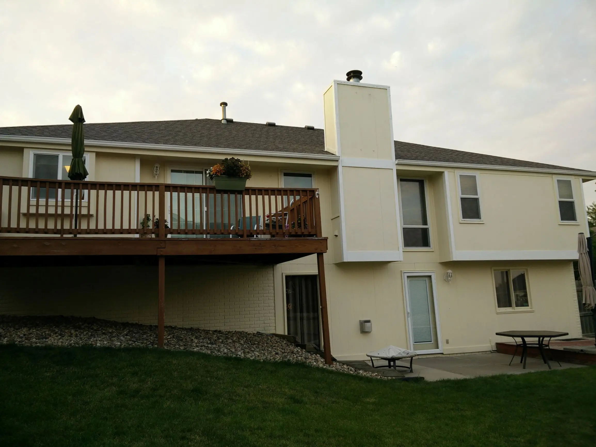 Yellow house with white trim and a brown deck painted by Omaha house painters