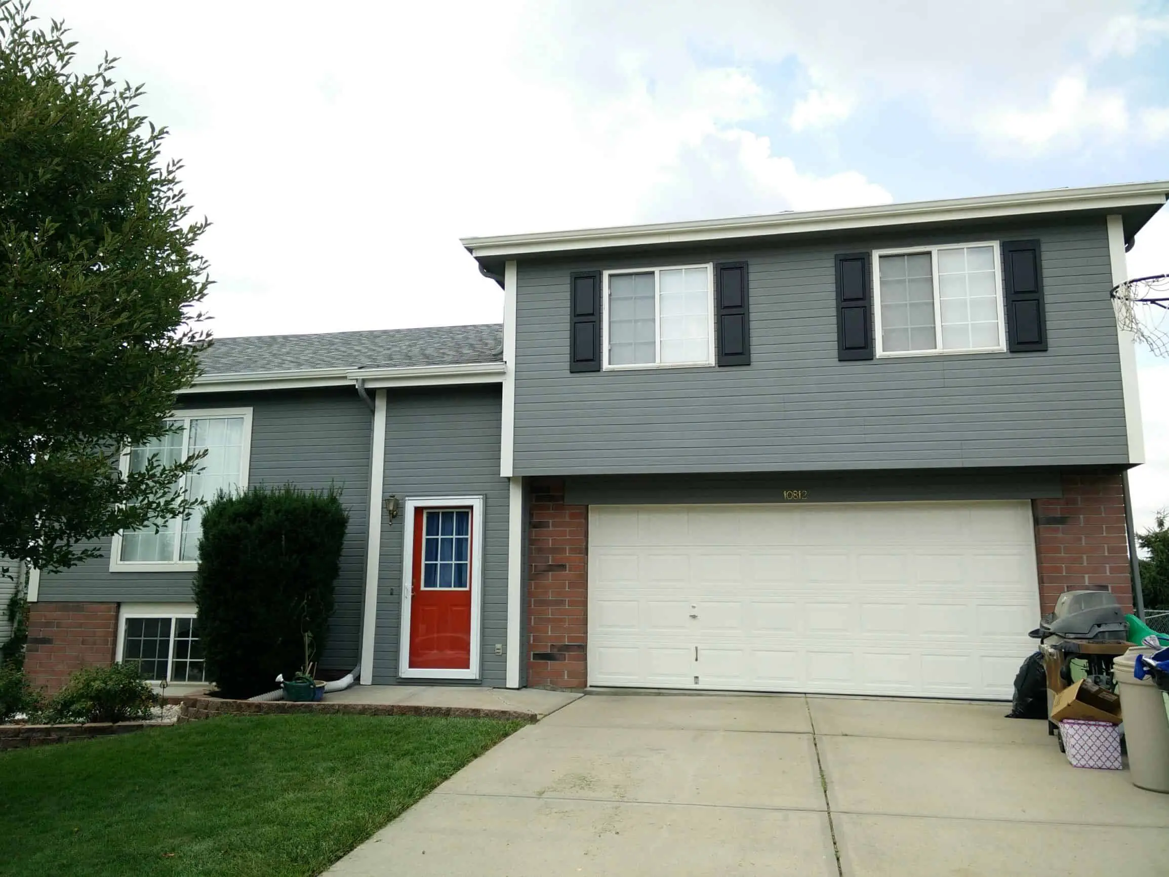 Light gray house with white trim, a red door, and black shutters painted by Omaha house painters